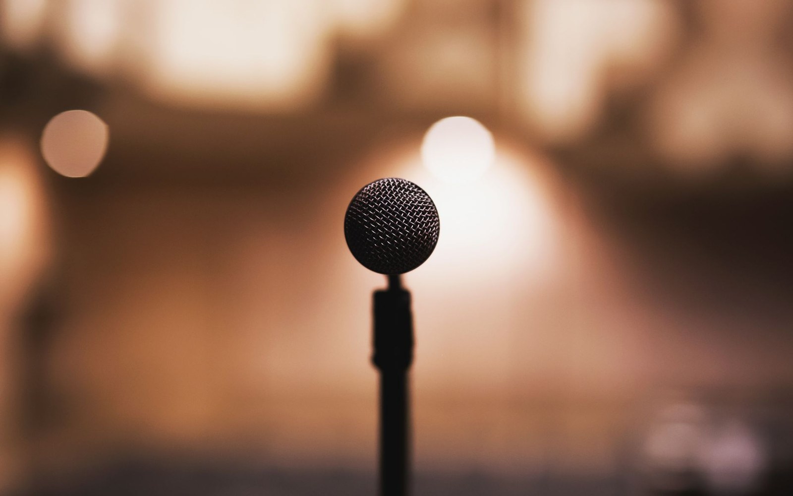A microphone on a stand against a blurred, warmly lit background